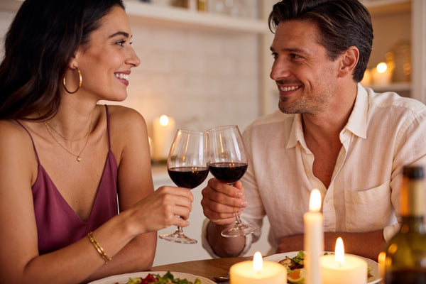 Cuplu la o cină acasă la lumina lumânărilor, ciocnind pahare de vin